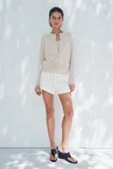 Chaqueta color crema de punto con lana, cuello redondo, manga larga y cierre frontal con botones.