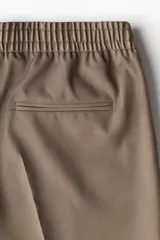 Pantalón de vestir color beige, de corte slim fit, con cintura elástica y cordón ajustable.