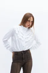 Camisa blanca de algodón con broderie y volados en cuello alto y puños.