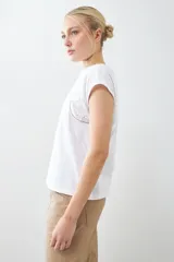 Remera blanca de algodón con cuello redondo y mangas cortas con detalle de broderie y vainillas.