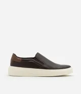 Championes slip on de cuero color marrón oscuro con detalle de cuero marrón claro en el talón y suela de goma color crema.