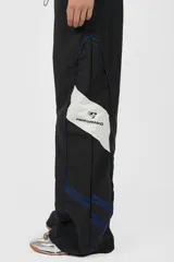 Pantalón deportivo gris de nylon, de calce recto y tiro medio, con elástico en la cintura, cordones ajustables y detalle de recorte con vivo a contratono en los laterales.