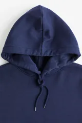 Canguro azul marino de corte holgado, con capucha forrada ajustable con cordón, hombros caídos, bolsillo tipo canguro y puños y bajo acanalados.
