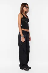 Pantalón cargo color arena de corte recto y tiro bajo, con recortes y presillas dobles en la cintura. Tiene acceso mediante cierre de nylon y botón personalizado, seis bolsillos laterales y dos en la espalda con tapa y botón snap a presión.
