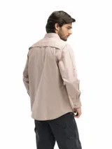 Camisa negra de manga larga con dos bolsillos frontales con tapa y velcro. Tiene la opción de arremangado con presilla y botón para mantenerla fija. Cuenta con una abertura posterior que favorece la ventilación.