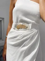 Vestido largo blanco de crepé, con breteles finos, falda irregular en capas y cinturón anudado con aplique de alpaca y ágata.