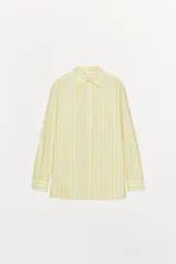 Camisa tipo pijamera a rayas amarillas y blancas, confeccionada en hilatura con algodón y lino. Tiene cuello solapa, manga larga con puños y cierre frontal con botones.