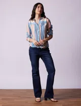Camisa de gasa estampada a rayas verticales de color celeste, blanco, naranja y marrón. Tiene cuello con solapa, escote en V, abertura central con botones, bolsillo aplicado en el pecho y terminación anudada en la parte delantera.