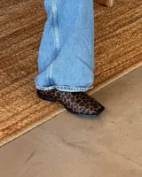 Suecos con estampado animal print en tonos marrones y negros, con detalle de triángulo dorado en el empeine.