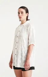 Camisa blanca con bordado de flores blancas, de manga corta y corte recto.