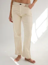 Pantalón de gabardina color crema, de corte recto, con alforzas verticales en los laterales.