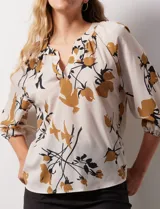 Blusa de gasa verde con estampado floral blanco y celeste, cuello a la base con escote en V y mangas 3/4 fruncidas.