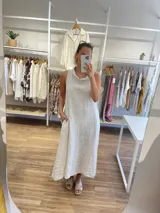 Vestido largo sin mangas color azul claro, confeccionado en lino, con cuello tipo buche o drapeado. Presenta un calce holgado y bolsillos laterales.