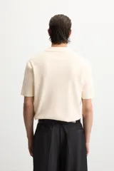 Polo color crema de punto, corte regular fit, cuello solapa con abertura frontal y manga corta.