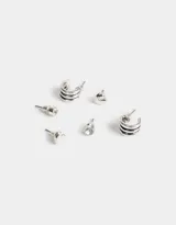 Set de aros plateados con diferentes diseños: aros tipo argolla con tres líneas horizontales, aros tipo botón con forma de corazón y aros tipo botón con strass.