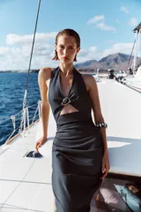 Vestido midi de cuello halter con escote pico y aplique metálico. Presenta una abertura delantera, frunces laterales en la cintura y abertura en la espalda. Cierre trasero con cremallera oculta.