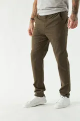 Pantalón chino color beige, de corte slim, con bolsillos laterales y traseros. Se ajusta a la cintura con cinturón de cuero marrón.