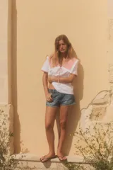 Camiseta blanca de cuello bobo con terminaciones bordadas y detalle de lazo en el delantero. El cuello y las mangas cortas son de tela a cuadros vichy color salmón.