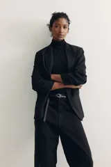 Blazer negro entallado confeccionado en mezcla de viscosa, con hombreras, solapas de muesca, mangas tres cuartos fruncidas y bolsillos delanteros con solapa. Sin cierre.