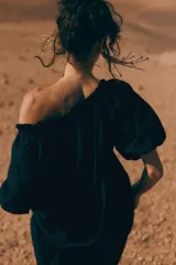 Vestido largo negro con escote cuadrado, cordón ajustable con borlas de cadena, mangas cortas abullonadas con forro y ribete elástico oculto, y costura fruncida bajo la cadera.