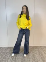 Sweater amarillo de cuello alto con botones decorativos en los puños.