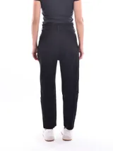 Jean negro de tiro alto con cintura fruncida y cierre de botón. Corte mom fit, ajustado en la cintura y más holgado en la cadera y muslos, con puños doblados en el tobillo.