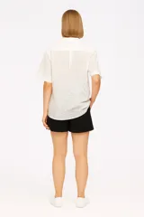 Camisa blanca de algodón con broderie, corte holgado, cuello camisero y mangas cortas.