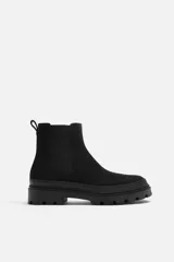 Bota Chelsea negra de cuero con acabado serraje, caña baja, puntera redondeada, tirador trasero y suela track con volumen.