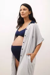Camisa maternal gris claro de viscosa suave, con cuello camisero azul marino, cierre frontal con botones, mangas cortas y bolsillo lateral.