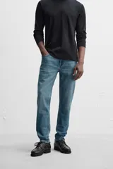 Pantalón de jean azul oscuro, corte slim fit, tiro medio, cinco bolsillos, tejido elástico y efecto lavado.