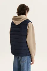 Chaleco puffer azul marino con cierre frontal, cuello alto y dos bolsillos con solapa en el pecho.