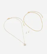 Conjunto de collar doble dorado, uno con cadena de eslabones finos y dije de flor con incrustaciones de zirconia y otro con cadena de eslabones retorcidos. Incluye caravanas tipo botón con zirconia.