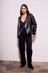 Campera negra estilo biker confeccionada en cuero vegano, con cuello solapa, cierre asimétrico y bolsillos con cremallera.