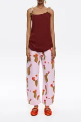 Pantalón de jean color lila con estampado de cactus marrones con flores naranjas. Corte recto, tiro medio y largo tobillero.