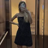 Vestido corto negro con estampado de líneas onduladas plateadas y tirantes de cadena metálica.