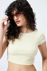 Top corto de punto acanalado color rosa, con silueta ajustada, escote redondo y ribetes blancos en cuello y mangas.