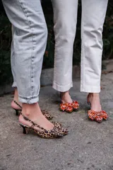 Zapato de tacón destalonado con estampado animal print en tonos naranja y marrón, con lazo doble en la parte delantera y tira trasera con hebilla. Tacón cuadrado de 2,5 cm y suela de cuero.