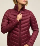Campera puffer ultraligera color marrón, confeccionada en poliamida acolchada, con cuello alto y cierre por cremallera. Incluye bolsita con cordón.