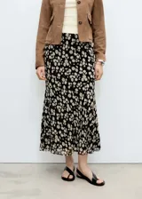 Falda midi negra de gasa con estampado de pequeñas flores blancas.