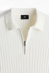 Remera polo de manga corta color crema, en tejido de punto acanalado de mezcla de algodón, con cuello clásico y medio cierre con cremallera.