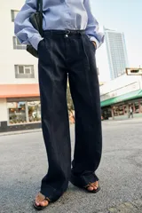 Jeans de tiro alto con corte bootcut, confeccionados en denim azul oscuro. Presentan costuras verticales decorativas en el frente, bolsillos laterales y cinturón del mismo tejido con hebilla metálica.