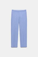 Pantalón de vestir celeste confeccionado en hilatura con lino, de tiro medio con bolsillos delanteros y falsos bolsillos traseros. Tiene abertura lateral en el bajo y cierre frontal con cremallera y ganchos metálicos.