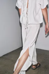 Top de lino color blanco, con cuello redondo y mangas cortas. Detalle de abertura en la espalda ajustable con lazadas.