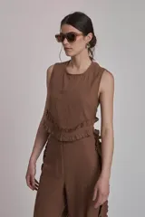 Conjunto de dos piezas color marrón, compuesto por un top sin mangas con volado en el ruedo y un pantalón ancho de tiro alto con volados decorativos a lo largo de las costuras laterales.