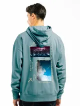 Canguro beige de corte oversize con capucha y bolsillo tipo canguro. Presenta un estampado pequeño en el pecho con un personaje de flor y la inscripción "FORUM IND".