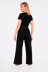 Pantalón cargo de jean color negro con corte ancho, bolsillos laterales y detalle de tachas plateadas en los laterales.