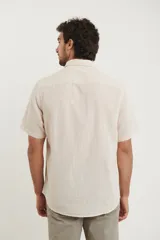 Camisa sport de manga corta color verde oliva, línea premium, con cuello clásico, cierre frontal con botones de coco y bolsillo de parche en el pecho. Confeccionada en lino y algodón.