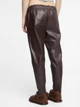 Pantalón negro de cuero sintético con corte slim fit, cintura elástica con cordón ajustable y bolsillos laterales. Acabado vintage.