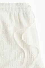 Short blanco con textura arrugada, cintura elástica y cordón ajustable.