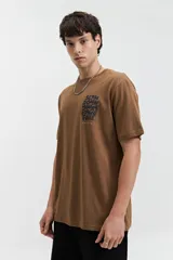 Remera marrón de manga corta con cuello redondo y estampado frontal con la frase "Slow down you're doing fine" en letras negras.